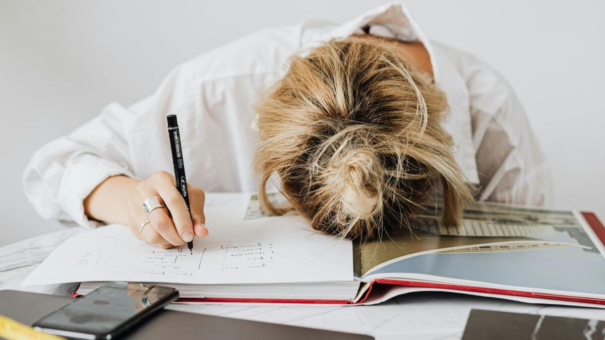 Unavená žena v práci hlavou leží na deskách s papíry