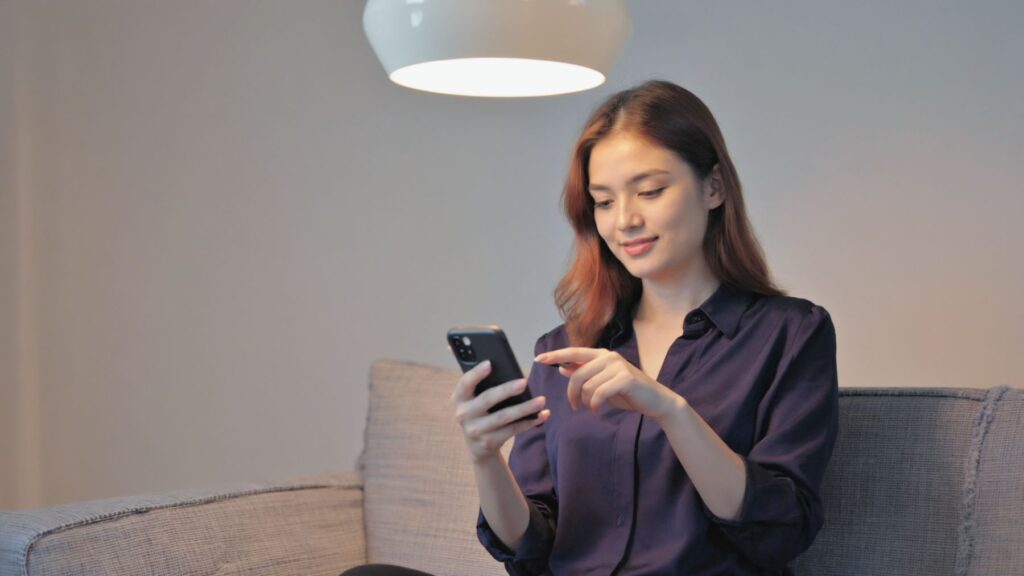 Žena nastavuje na telefonu chytré osvětlení.