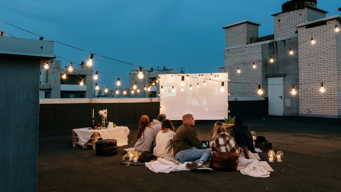 Přátelé večer sledují film venku v letním kinu.