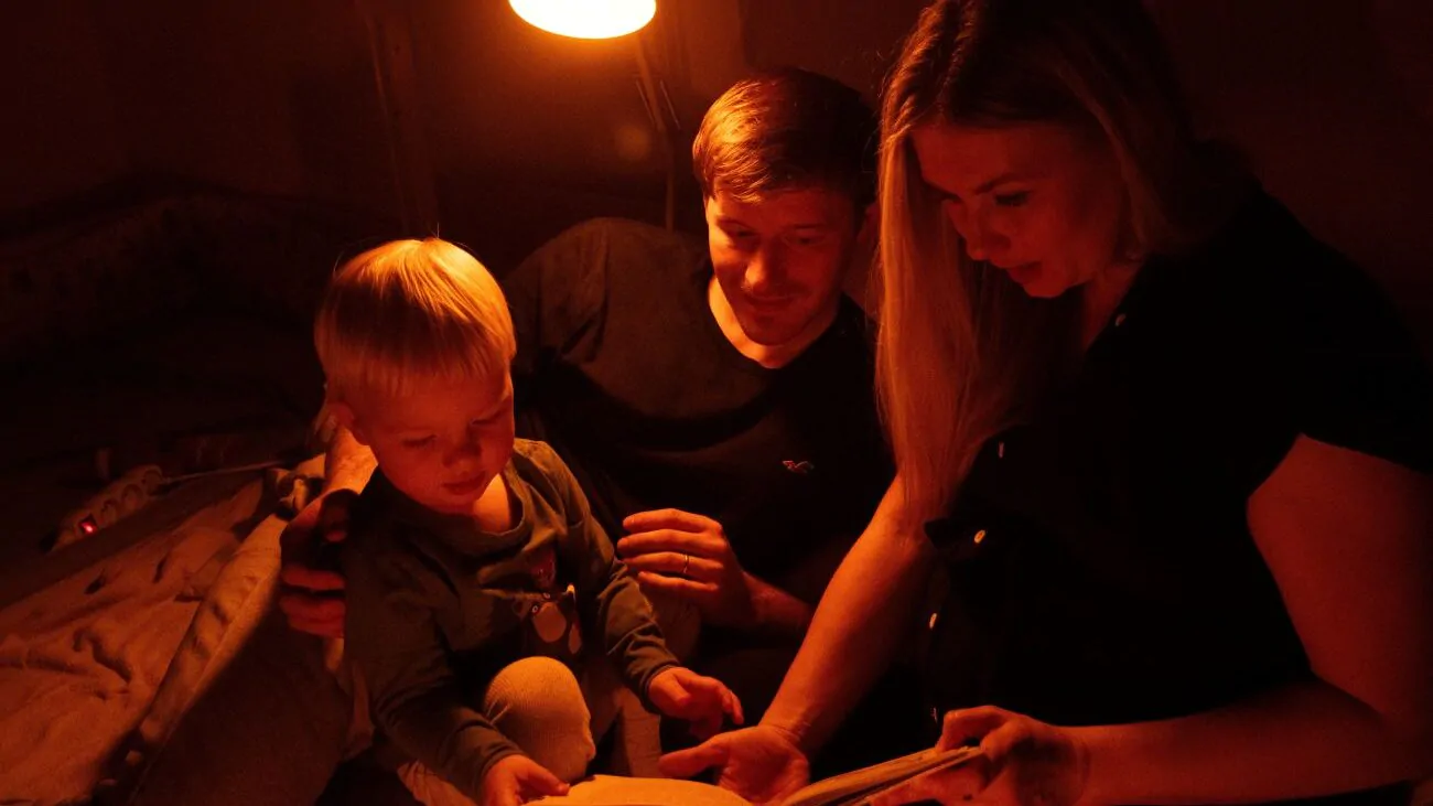 Rodiče s dítětem si večer čtou pohádku a svítí jim večerní lampa Oranžovka.