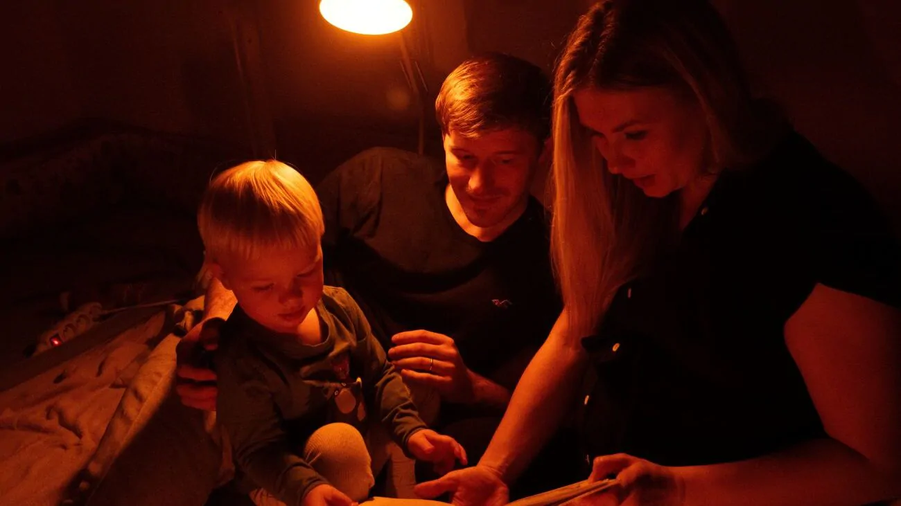 Rodiče s dítětem si večer čtou pohádku a svítí jim večerní lampa Oranžovka.