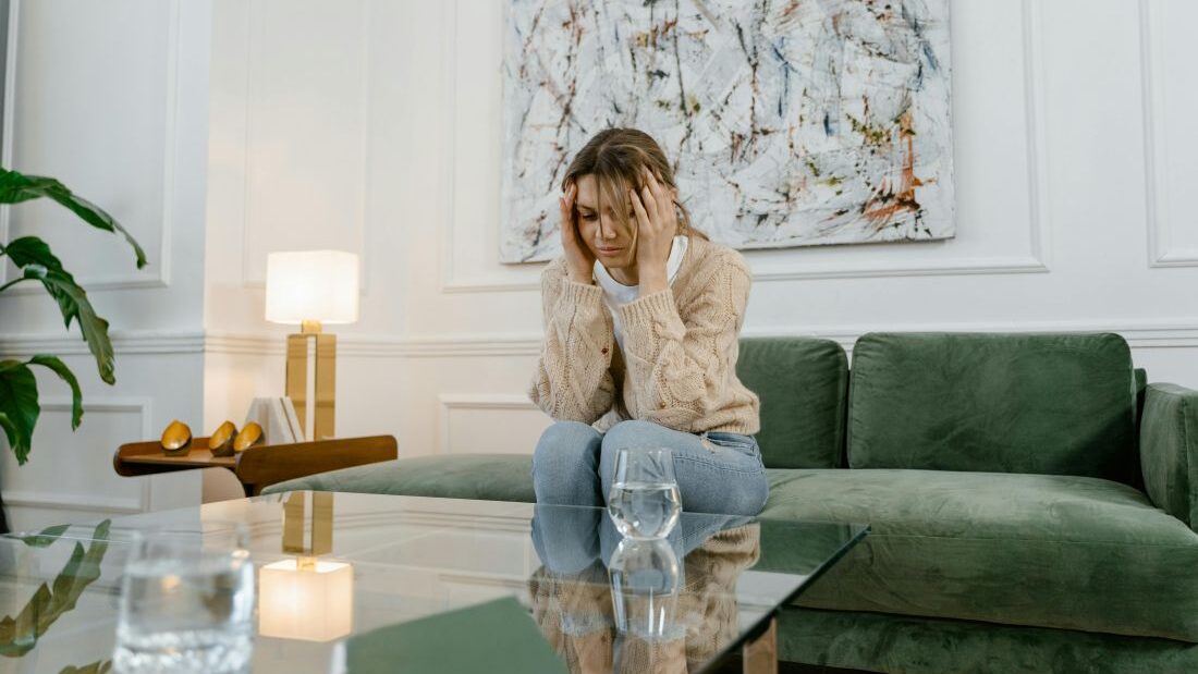 Unavená žena sedí na gauči