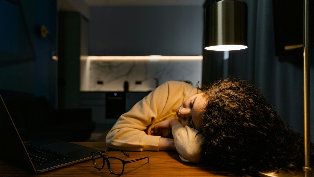 Unavená žena má hlavu položenou na stole.