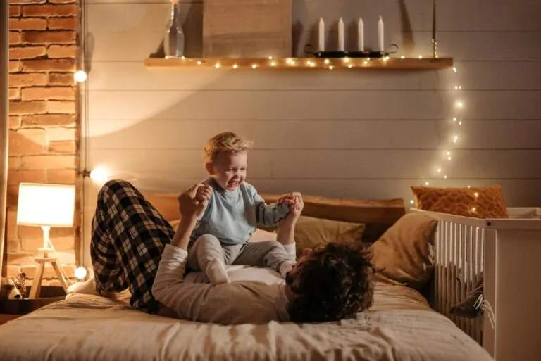 Otec s dítětem leží na posteli a hrají si