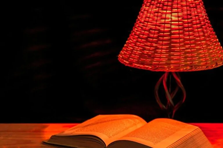 Lampa svítí červeným světlem na knihu