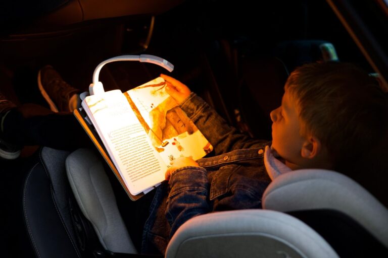 Chlapeček si čte v autě a svítí mu lampička Oranžovka