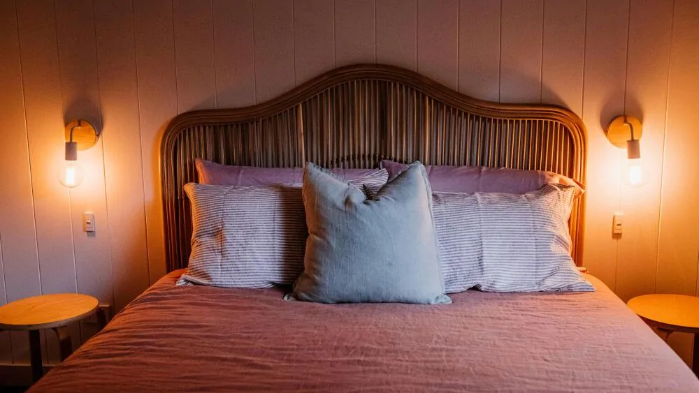 Postel v ložnici a rozsvícené lampičky.