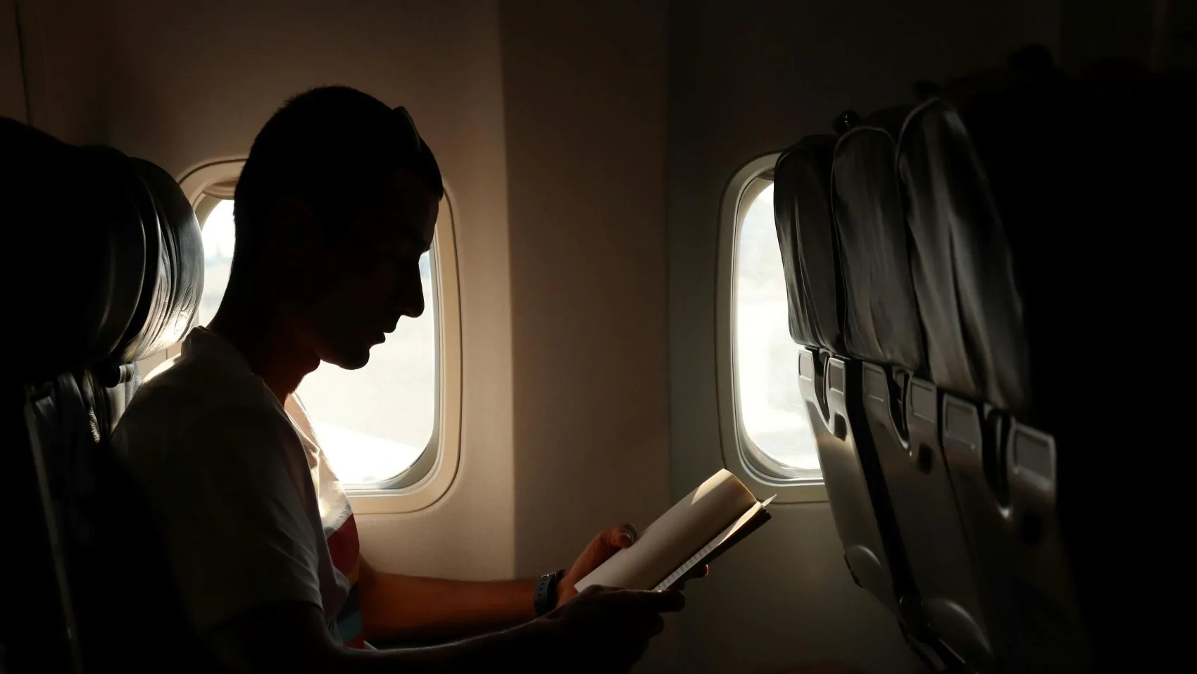 Muž si čte v letadle