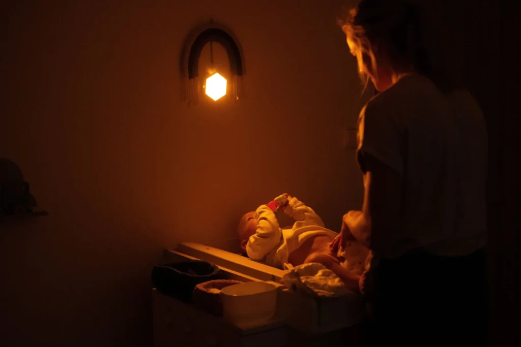 Žena přebaluje miminko a svítí jí noční světlo Oranžovka