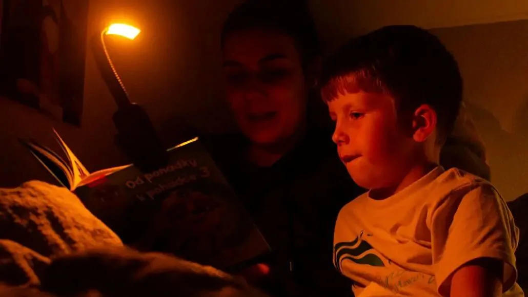 Maminka čte synovi pohádku a svítí si večerní lampičkou Oranžovkou