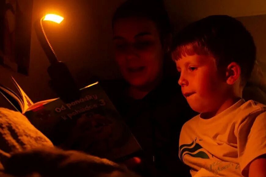 Maminka čte synovi pohádku a svítí si večerní lampičkou Oranžovkou