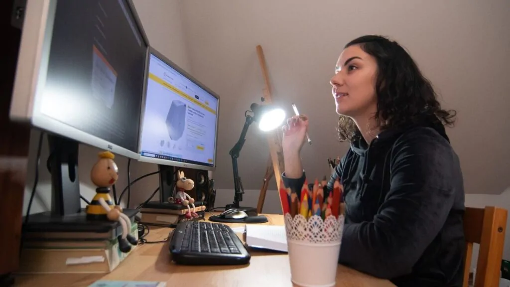 Žena pracuje na počítači a u toho jí svítí Denní stolní lampa Oranžovka